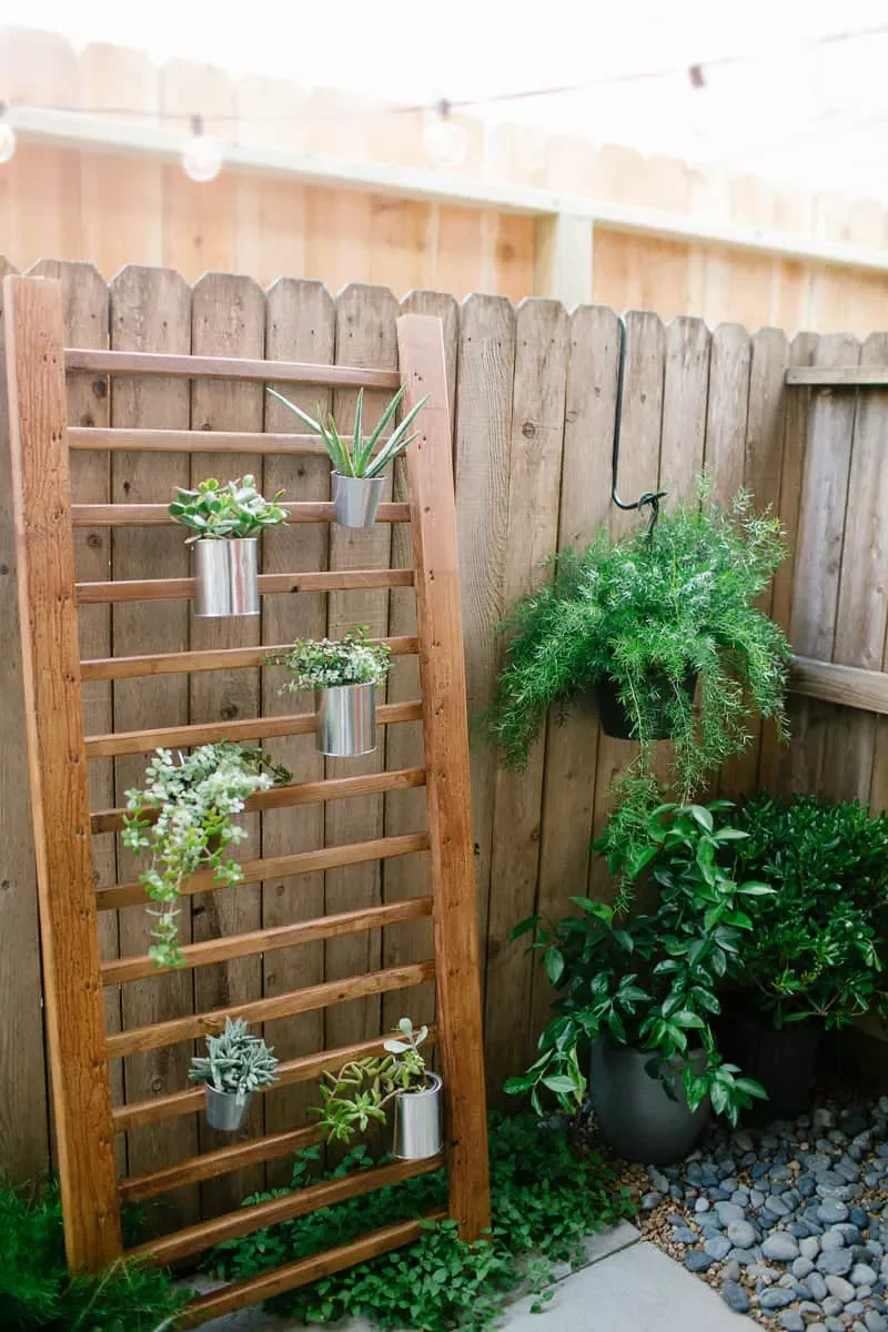 30 Creative Fence Decorating Ideas to Transform Your Yard 14 Lean an Upcycled Plant Stand Against the Fence